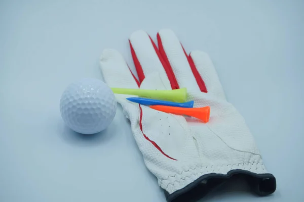 Beyaz eldivenli eller beyaz arka planı olan bir golf topu tutuyor..                                
