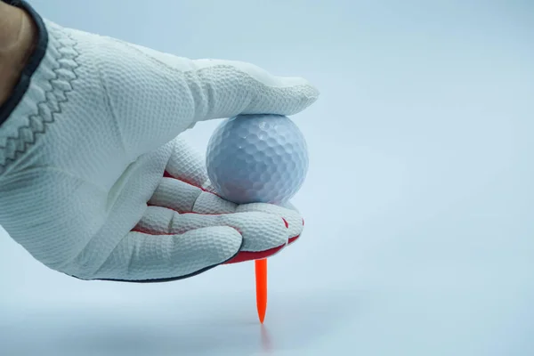 White glove hands are holding a golf ball with a white background.