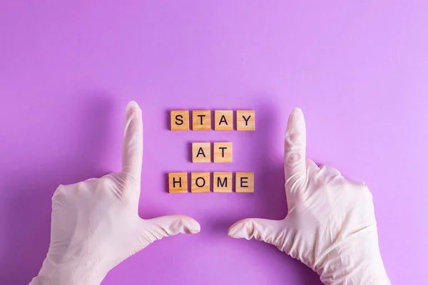 Stay at home hands in rubber gloves quarantine self-isolation on a purple background