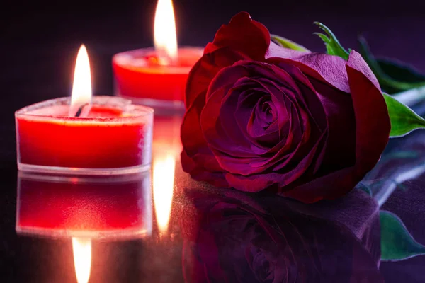 Красная роза и горящие свечи — стоковое фото