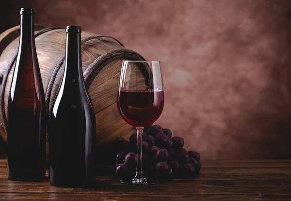 Bicchiere di vino rosso e due bottiglie — Foto Stock