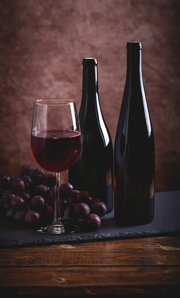 Bicchiere di vino rosso e due bottiglie — Foto Stock