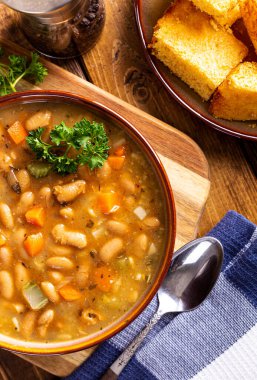 Havuçlu fasulye çorbası, kase içinde kereviz ve ahşap masada mısır ekmeği.