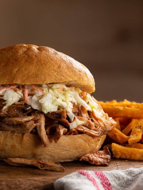 Barbekü tavuk sandviçi, lahana salatası ve patates kızartması. Kırsal kesim tahtası ve fotokopi makinesi.