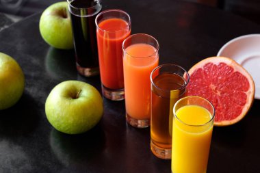 Portakal, elma, domates, havuç, cam bardakta vişne suyu siyah bir zemin üzerinde elma, greyfurt ve nane.