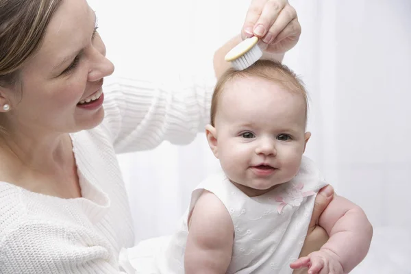 Madre cepillando el cabello del bebé —  Fotos de Stock