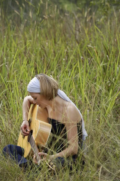Mujer tocando la guitarra en el campo — Foto de Stock