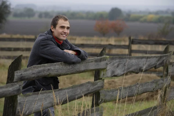 man leaning on country fence