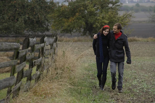 Casal andando ao lado de cerca — Fotografia de Stock