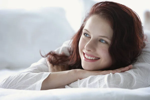 Woman lying on bed, smiling