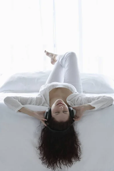 Жінка лежить на спині з навушниками один — стокове фото