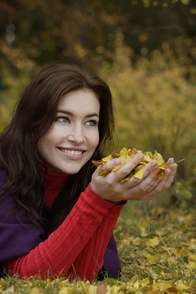 Jeune femme avec une poignée de feuilles d'or — Photo