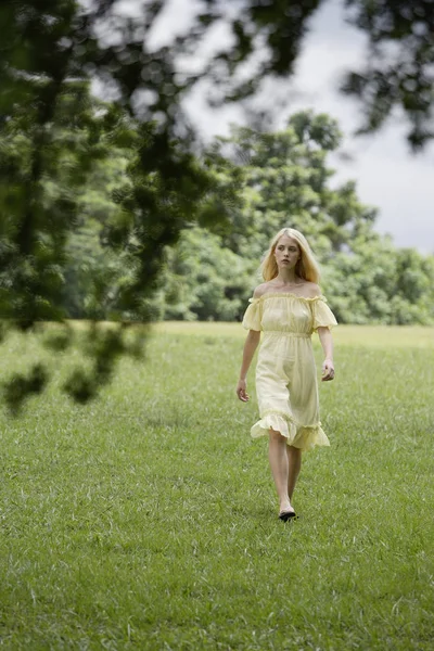 Vrouw in gele jurk in groene veld — Stockfoto