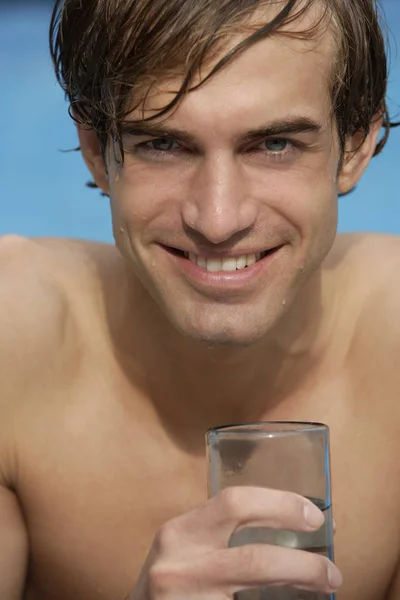 Joven en la piscina con vaso de agua —  Fotos de Stock