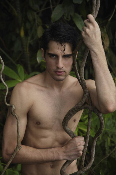Young man leaning on jungle vines