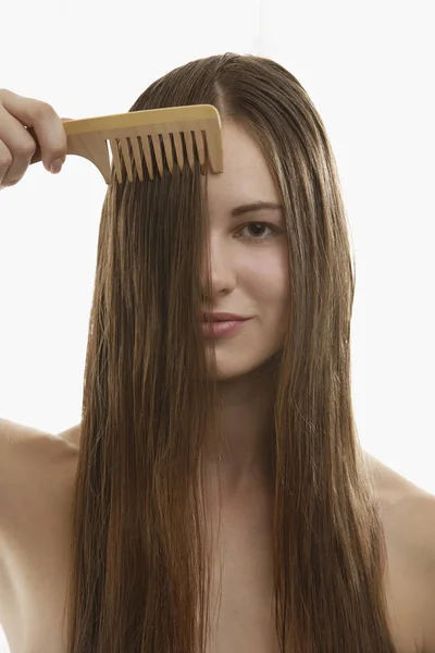 Mujer joven peinando pelo largo y castaño — Foto de Stock