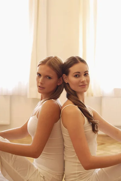 Two woman sitting back to back