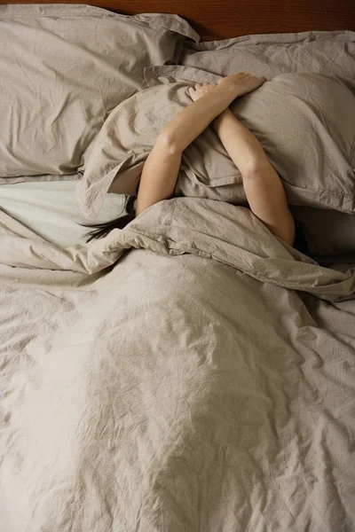 Mujer en la cama cubriéndose la cabeza —  Fotos de Stock