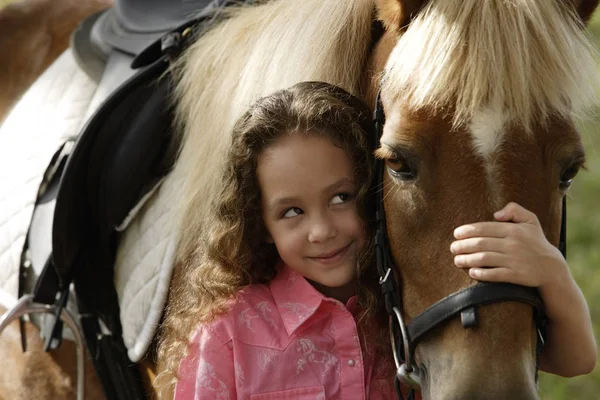 Chica joven abrazando la nariz de pony — Foto de Stock