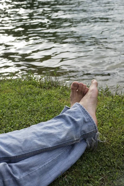 Молодой человек лежит на траве у озера — стоковое фото