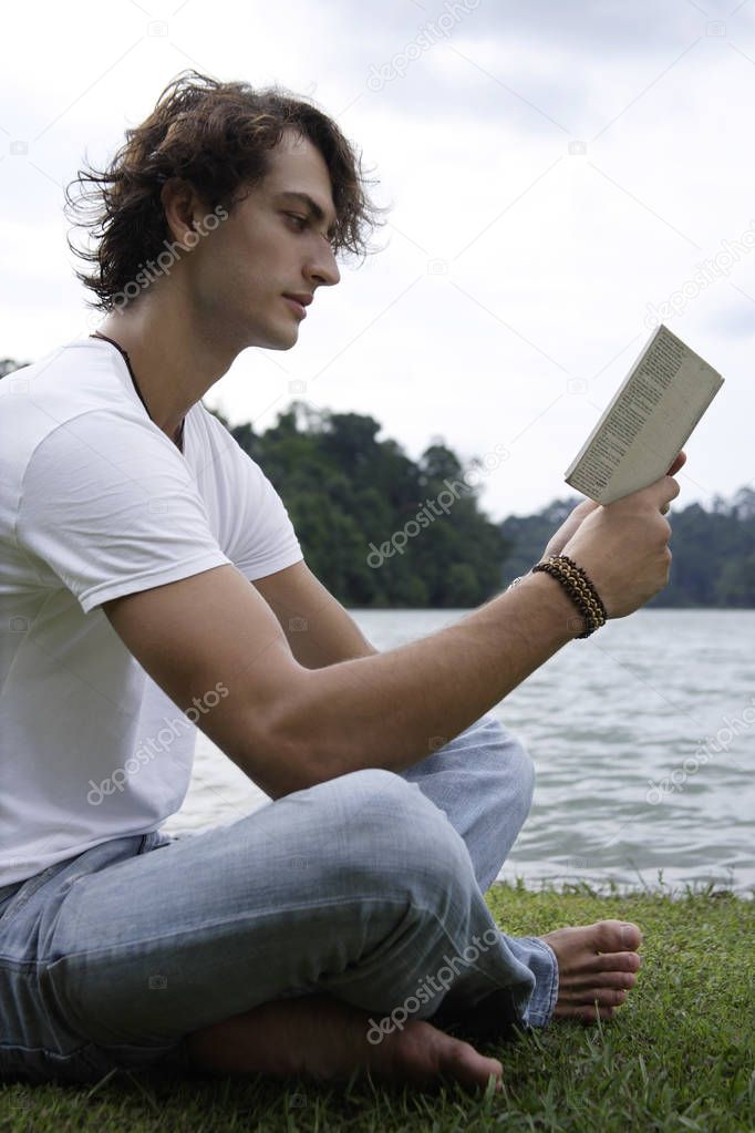 Young man reading, lakeside