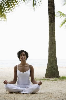Kumsalda yoga yapan bir kadın.