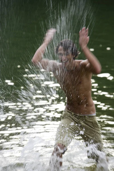 Junger Mann planscht Wasser in See — Stockfoto