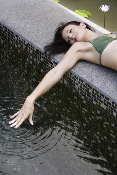 Mujer reclinada junto a la piscina — Foto de Stock