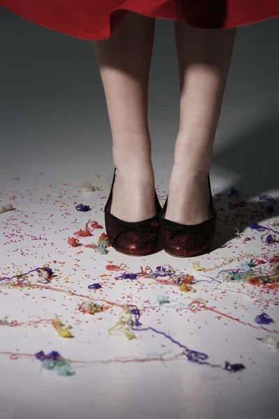 Mujer usando zapatos rojos con confeti en el suelo — Foto de Stock