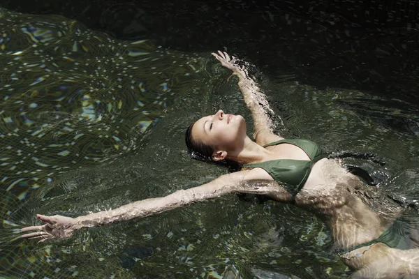 Mujer flotando en la piscina — Foto de Stock