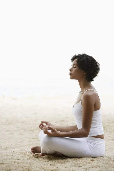 Kumsalda yoga yapan bir kadın.