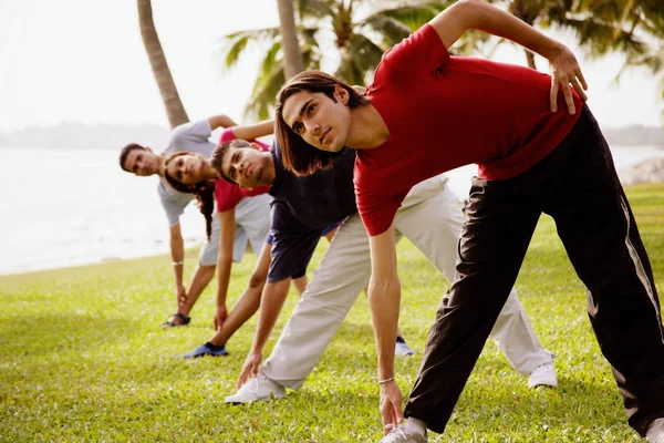 Jovens adultos fazendo exercícios de alongamento — Fotografia de Stock