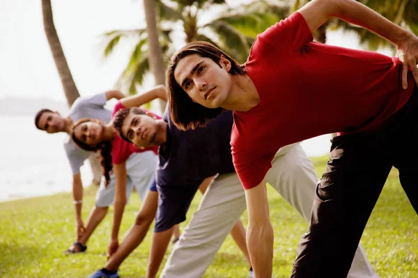 Jovens adultos fazendo exercícios de alongamento — Fotografia de Stock