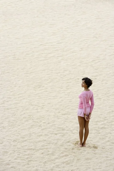 Mujer vistiendo de rosa y de pie sobre arena — Foto de Stock