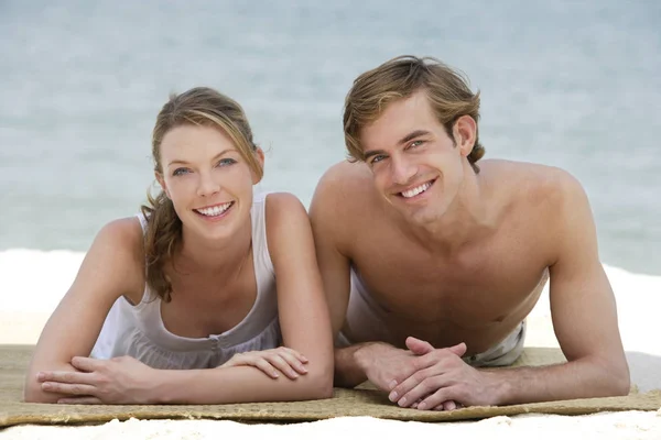 Junges Paar liegt auf Strandmatte — Stockfoto