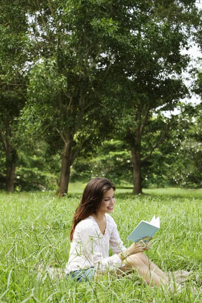 Vrouw op gras lezen van een boek — Stockfoto