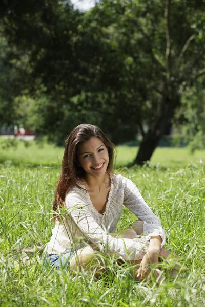 Femme assise sur l'herbe souriant — Photo