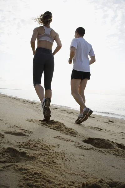 Пара бегущая по пляжу — стоковое фото