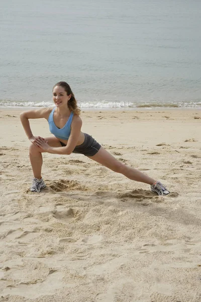 Mulher se alongando na praia — Fotografia de Stock