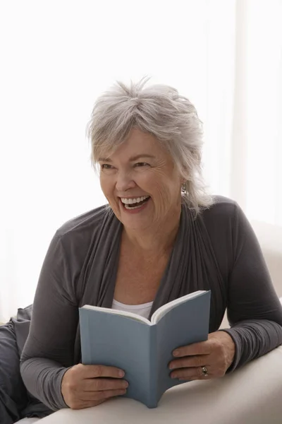 Mujer sonriendo mientras lee libro — Foto de Stock