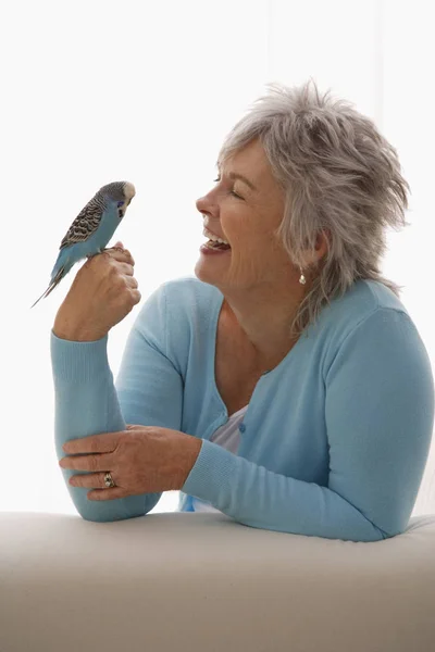 Mujer mayor sosteniendo pájaro azul — Foto de Stock