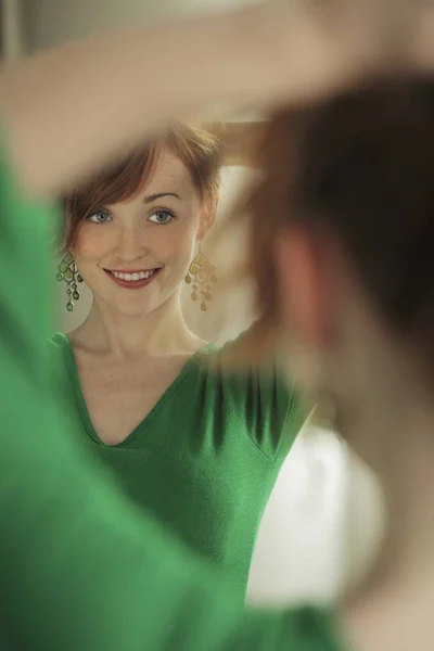 Vrouw probeert op oorbellen in spiegel — Stockfoto