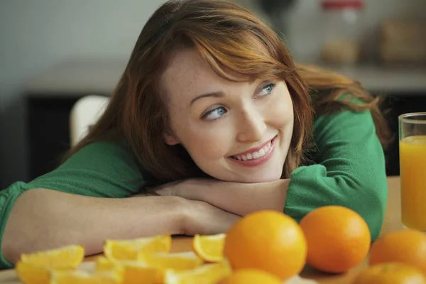 Frau liegt mit Orangen auf Tisch — Stockfoto