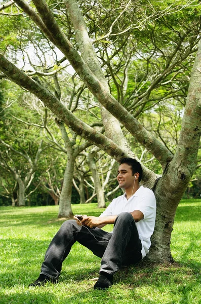 Ung man sitter under träd — Stockfoto
