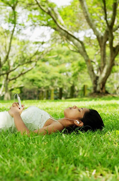 Femme écoutant de la musique allongée sur l'herbe — Photo