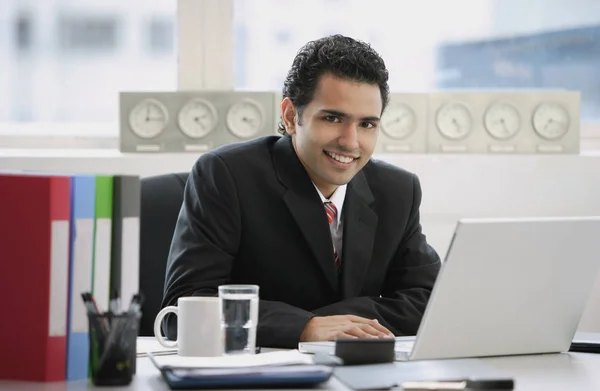 Empresario sentado en la oficina, sonriendo a la cámara — Foto de Stock