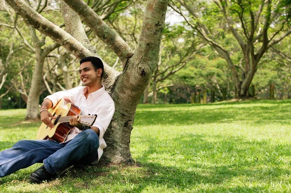 Young man sitting under tree Royalty Free Stock Photos