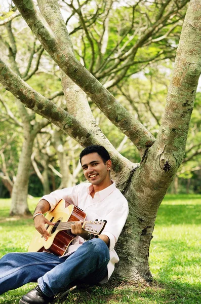Young man sitting under tree Royalty Free Stock Photos