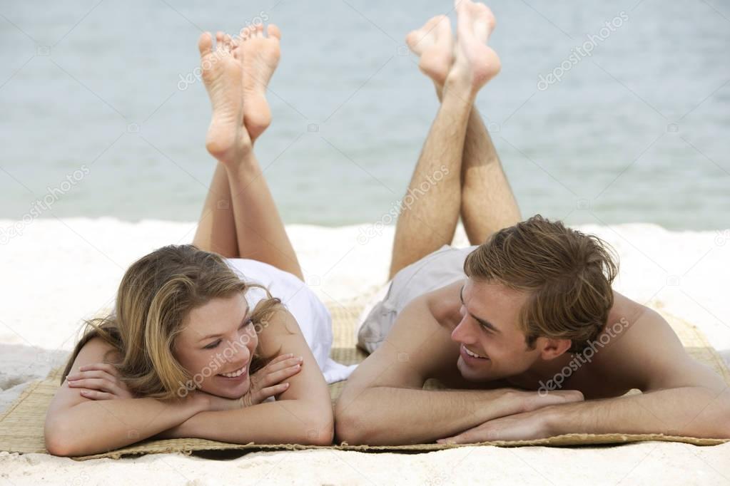 couple relaxing on beach mat