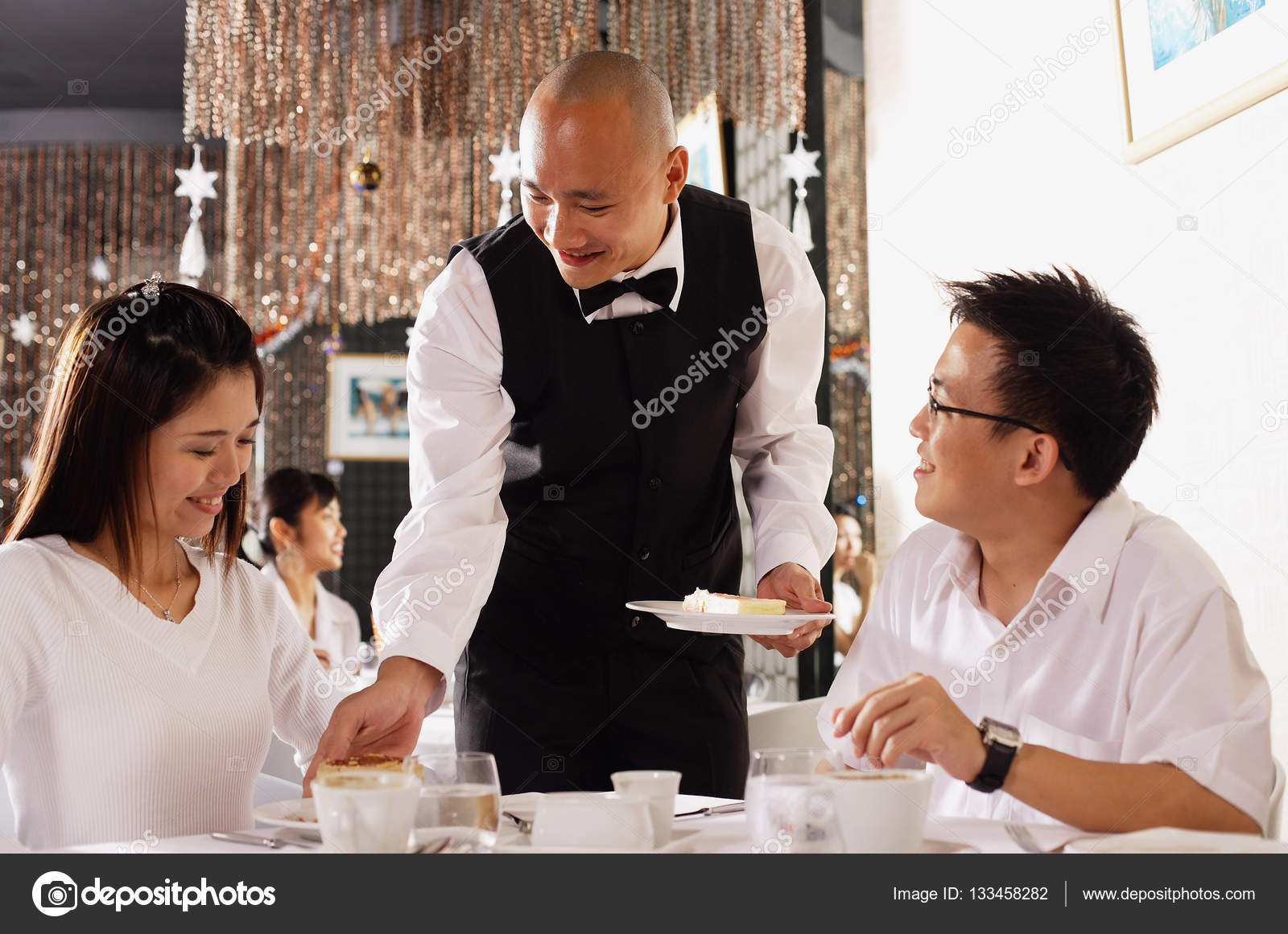 Waiter serving customers in restaurant — Stock Photo © MicrostockAsia 133458282